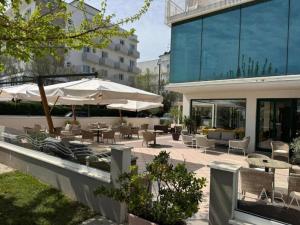 a patio with tables and chairs and umbrellas at Hotel Centrale FRONTE MARE in Milano Marittima