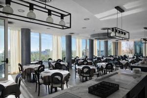 a restaurant with tables and chairs and large windows at Hotel Centrale FRONTE MARE in Milano Marittima