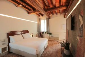a bedroom with a white bed and a television at Relais Barchessa Molon in Campo di Pietra