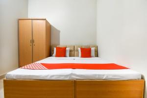 a bedroom with a bed with orange and white pillows at Hotel O Sabtera Homes in Kharar