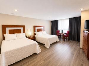 ein Hotelzimmer mit zwei Betten und einem Fernseher in der Unterkunft Hotel Finisterre in Mexiko-Stadt