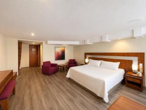 ein Hotelzimmer mit einem Bett und zwei Stühlen in der Unterkunft Hotel Finisterre in Mexiko-Stadt