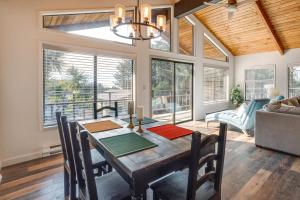 a dining room with a table and chairs and windows at Tree-Lined Gold Beach Retreat w/ Multiple Decks! in Gold Beach