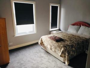 a bedroom with a bed and two windows at Sandhurst guest house in Bedford