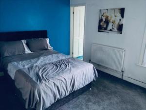 a bedroom with a bed with a blue wall at Sandhurst guest house in Bedford