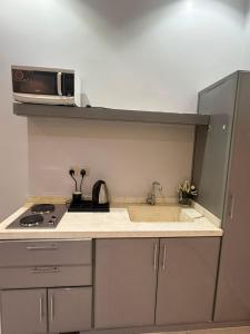 eine Küche mit Spüle und Mikrowelle in der Unterkunft لافيرا للشقق الفندقيه - Lavera Apartments in Al-'Ula + 11 Fotos