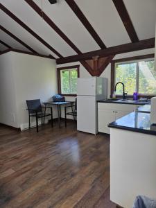 a kitchen with white cabinets and a table with chairs at Noah's Ark Campground in Malakwa