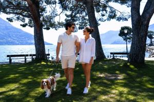 a man and woman walking a dog on a leash at Rivalago - Lake front apartment on Lake Promenade in Brissago +3 photos