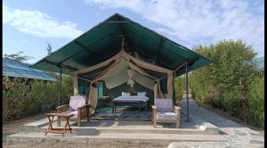 a tent with chairs and a bed in it at Kambu Mara Camp in Sekenani