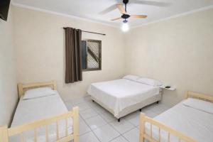 a bedroom with two beds and a ceiling fan at Apartamentos PraiaMar in Ilha Comprida