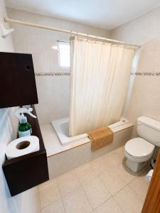 a bathroom with a toilet and a shower curtain at Aguacatl Cozumel a 3 cuadras del mar in Cozumel