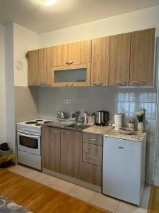 a kitchen with wooden cabinets and a white stove top oven at Apartman 14 in Doboj