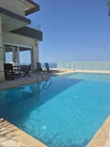 a swimming pool with chairs and a building at Villa mnar 3 chambre en haut in Tangier
