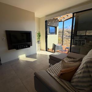 a living room with a couch and a flat screen tv at Villamagna, cabaña con jacuzzi en Potrerillos in Potrerillos
