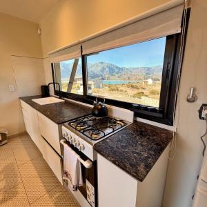 a kitchen with a stove and a large window at Villamagna, cabaña con jacuzzi en Potrerillos in Potrerillos
