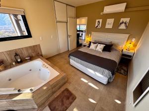 a bedroom with a bed and a bath tub at Villamagna, cabaña con jacuzzi en Potrerillos in Potrerillos
