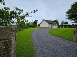 a gravel road leading to a white building and a field at Hill House Westport in Mayo