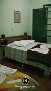 a bedroom with a bed with green and white sheets at Hotel São Luiz Iraí in Iraí +4 photos