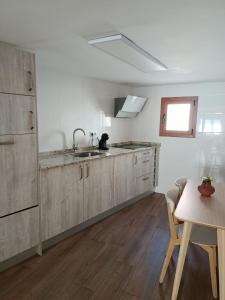 a kitchen with wooden cabinets and a sink and a table at La calma de Arnedillo in Arnedillo