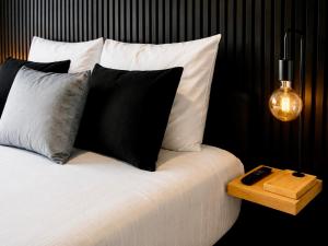 a bed with black and white pillows and a night stand at Charleroi Brussels Airport White Castle in Charleroi