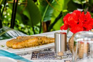 a plate of fish on a table with a red flower at KIGALI E6 APARTMENTs RESORTS in Kigali