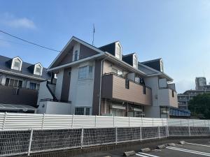 a house behind a fence next to a street at Guest House "Ro"Hieda B101 in Shimonoseki
