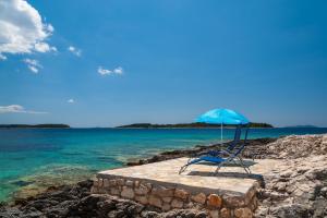 a blue chair sitting on a stone slab with the ocean at Apartments by the sea Cove Nova, Korcula - 11353 in Vela Luka