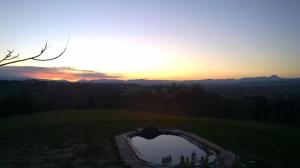 ein Sonnenuntergang über einem Teich auf einem Golfplatz in der Unterkunft alumbia in Petriolo
