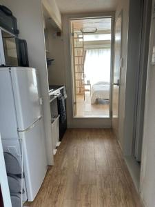a kitchen with a refrigerator and a door to a room at Guest House "Ro"Hieda B101 in Shimonoseki