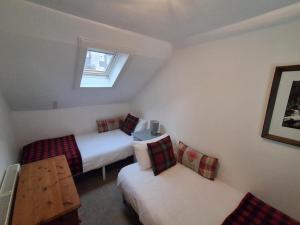 a small room with two beds and a window at Dunella Traditional Cottage in Callander