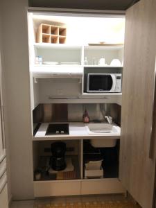 a small kitchen with a microwave and a refrigerator at Agréable studio au bord de mer. in Saint-François