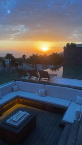 a sunset over a pool with a couch and chairs at Villa élite in Tangier