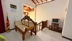 a living room with a bench and a television at Blissful Chateau in Batigama