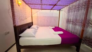 a small bed in a room with a purple ceiling at Blissful Chateau in Batigama