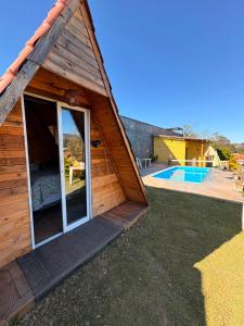 a small house with a large window and a pool at Chalé Pingo de Ouro Socorro SP in Socorro