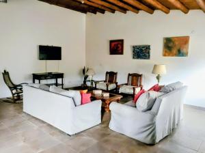 a living room with white couches and a tv at Refugio de Chacras in Ciudad Lujan de Cuyo