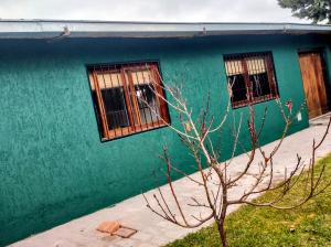 a green house with two windows and a tree at Refugio de Chacras in Ciudad Lujan de Cuyo