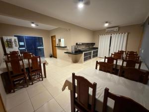 a dining room with tables and chairs and a kitchen at Point Hotel in Tanabi