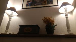 two lights on a shelf with a clock and a plant at La Terrasse d'Ozein in Ozein