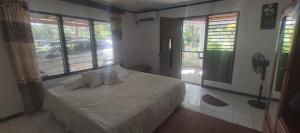 a bedroom with a bed in a room with windows at Ali's Homestay in Pacific Harbour