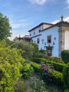 a white house with a garden of flowers and bushes at Quinta da Maínha - Charming Houses - com piscina privada in Braga