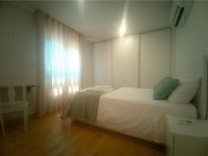 ein Schlafzimmer mit einem weißen Bett und einem Fenster in der Unterkunft Barcelos Habadia Espigueiro in Lijó
