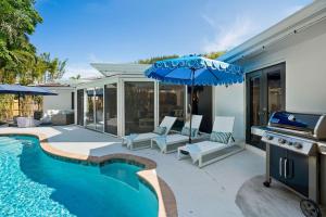 a house with a swimming pool and an umbrella at The Coastal Duo Escape in West Palm Beach