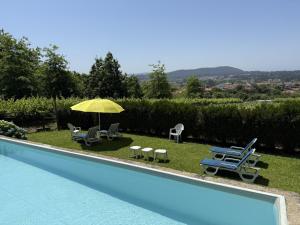 a swimming pool with chairs and a yellow umbrella at Paco d'Anha in Viana do Castelo