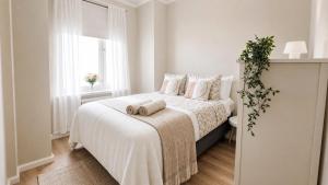 a white bedroom with a bed with two towels on it at GuestFirst- Modern Boho Charm in Kallio Helsinki Center in Helsinki