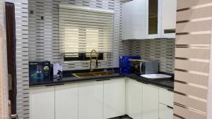 a kitchen with white cabinets and a sink at Zemira Apartments in Abuja