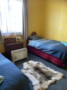 a bedroom with two beds and a rug on the floor at Waitomo Farmstay - Rimu Cottage 2 in Waitomo Caves