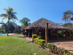 a hut with a grass roof next to a pool at Hotel Balneario Las Tinajitas in Choreti