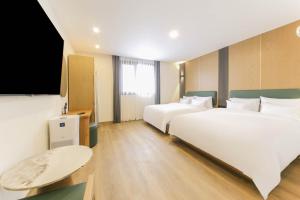 a hotel room with two beds and a flat screen tv at 군산 비욘드 호텔 in Sinp'ung