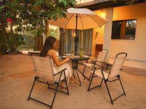 a woman sitting at a table with an umbrella at Claruá Chalés- Loft Caju- Pé direito duplo, 3min de carro do Rio- Conforto e Natureza dentro da cidade in Cavalcante